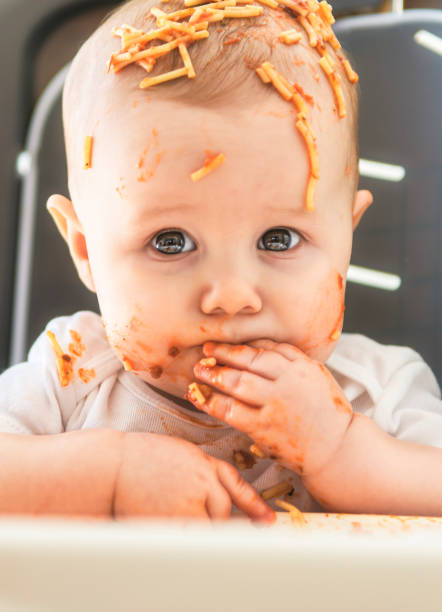 A Little baby eating her dinner and making a mess