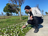 Man picking daisies in the public park on a sunny day
