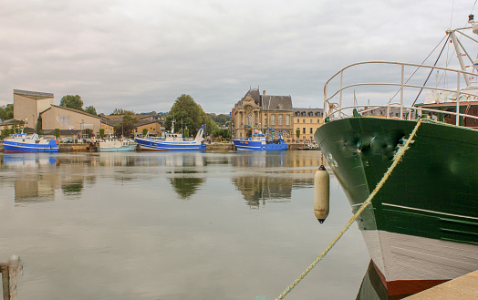 a scenic view of the port of Dieppe with fishing boats against the quay and reflection in calm water of the sea