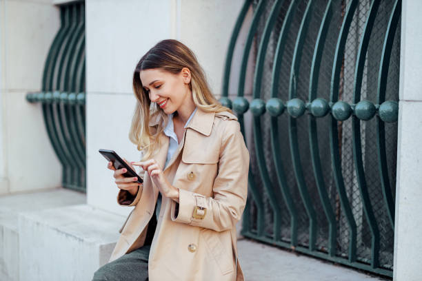 istock A trendy young lady is sitting outdoors downtown and texting messages. 2030916479