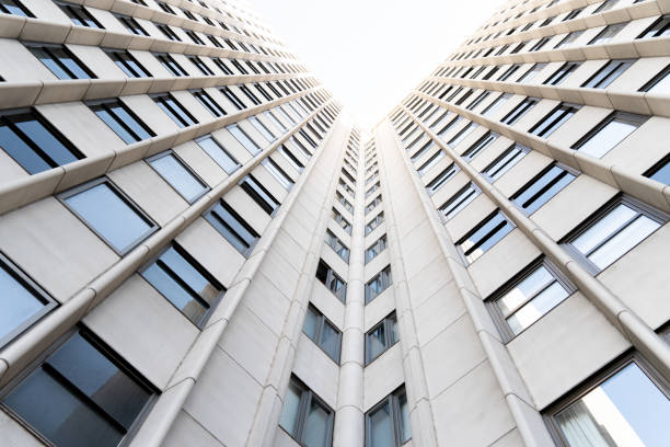 Very tall white building with glass windows seen from below.