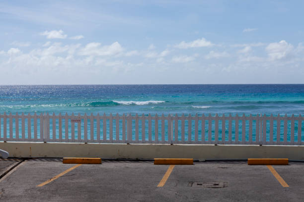 Structure of a weathered fence, originally green. Atlantic ocean with waves in the blurry background. Blue sky with white clouds. Galdar, Las Palmas, Gran Canaria, Canary Islands, Spain.
