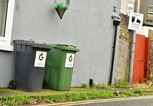 Rubbish/recycling bins outside a house in Dublin  with signage in Irish nearby