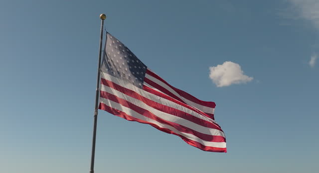 Patriotic Slow motion shot of an American Flag waving in the wind against blue sky