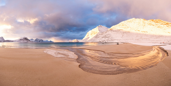 Clouds at dawn mirrored in the arctic sea surrounded by snow, Auckland, Nordland, Lofoten Islands, Norway