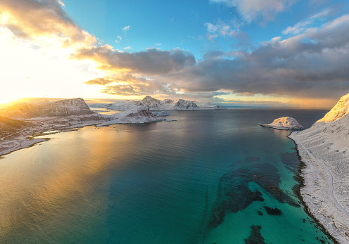 Aerial view of majestic mountains washed by waves of the cold sea at sunset, Unstad, Vestvagoy, Lofoten Islands, Nordland