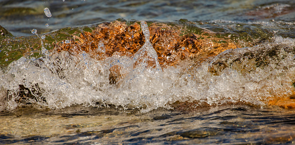 Waves washing over a rock near the shoreline of Lake Ontario.