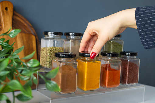 Cropped hand holding jar of spices on kitchen.
