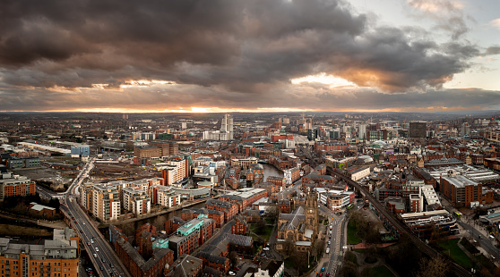 An aerial panoramic view of Leeds cityscape skyline with Leeds Dock and the River Aire running through the city with dramatic sky at sunrise