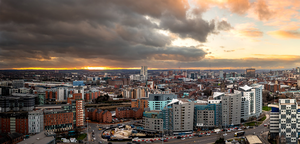 An aerial panoramic view of a Leeds cityscape skyline in West Yorkshire with modern apartment buildings dramatic sky at sunrise