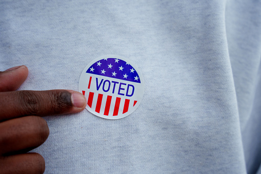 Close Up Hand of African American Man Pointing to an I Voted Sticker Place on His Shirt