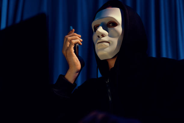 istock White criminal anonymous mask calling to IT owner to threaten ransom. Pecuniary. 2031096159