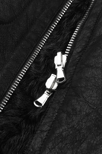 Double metal zipper on a black sheepskin coat from Shearling background close up