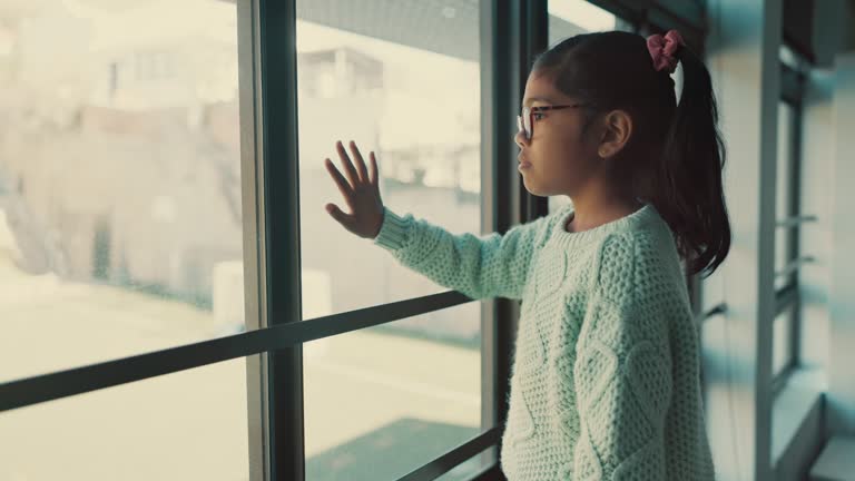 Hand, window and girl child with depression, anxiety or fear, terror or kidnap danger in a house. Mental health, stress and kid with anxiety from abuse, bullying or trauma, crisis or abandoned