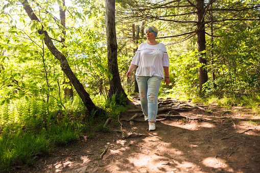 Mature blonde woman hiking on natural trails in the woods in Pocono Mountain Region in Pennsylvania
