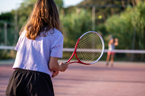two teenage girls play tennis on a sunny day