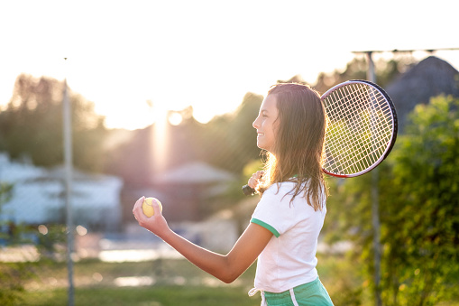 a teenage girl plays tennis and serves the ball