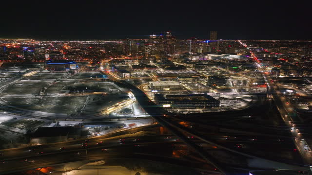 Downtown Denver snowy winter evening night city lights landscape aerial drone cinematic anamorphic i25 traffic highway Colorado Mile High DU Metro Eltiches Ball Arena pan slowly right motion