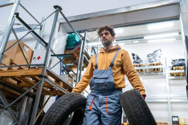 istock Warehouse worker carrying tires at storage room 2031269436