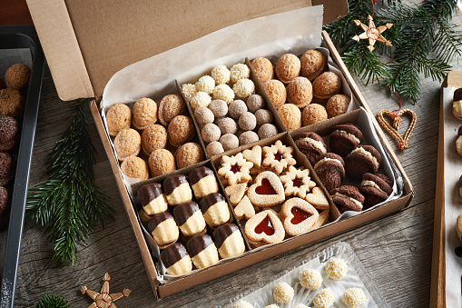 Variation of handmade Christmas cookies in a gift box on a wooden table with fir tree branches