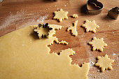 Cutting out shapes from rolled out dough to prepare Linzer Christmas cookies