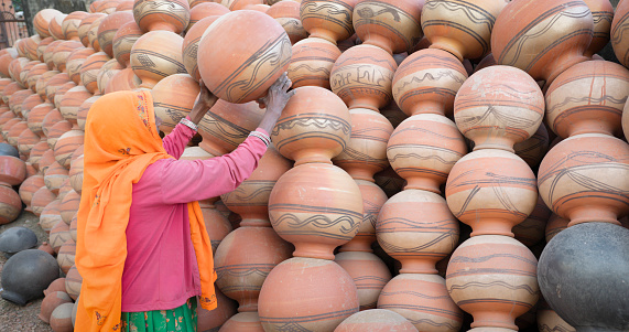 Indian woman arranges clay pots in The Pink City of Jaipur, Rajasthan, India. Jaipur is known as the Pink City, because of the color of the stone exclusively used for the construction of all the structures.