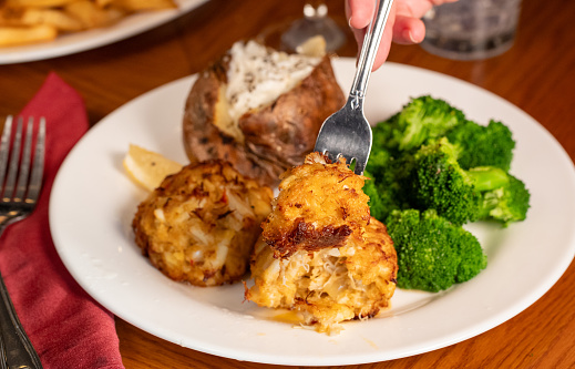 Action image of Jumbo Crab Cakes, Steamed Broccoli and Stuffed Baked Potato