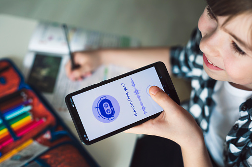 Happy boy using system AI Chatbot on mobile application to do his homework. Chatbot conversation, Ai Artificial Intelligence technology. Futuristic technology. Virtual assistant on internet.