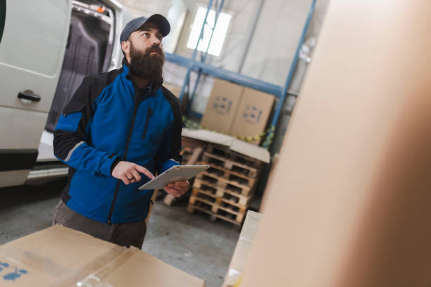 istock A bearded delivery man checks packages in a warehouse using a digital tablet 2031420011