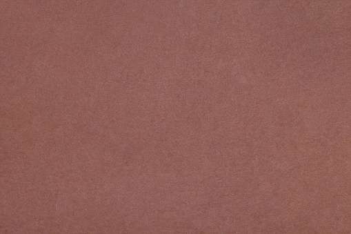 Paper background in monochromatic brown color with a fibrous texture. Paper background in brown color with empty space for text or advertisement. Uniform paper texture for packaging or background