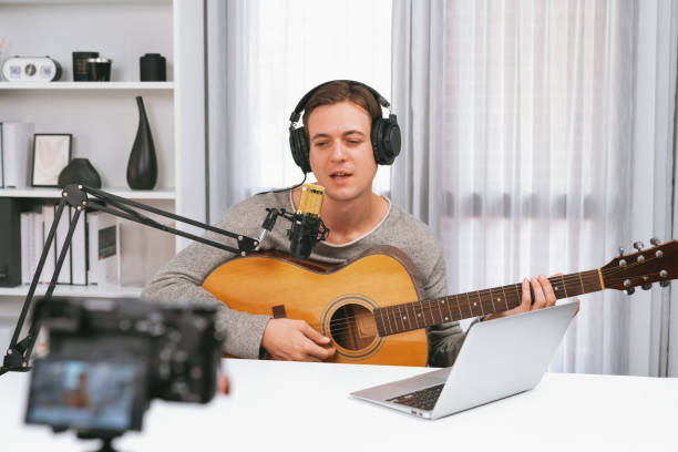 istock Smart singer recording by camera, playing guitar along singing. Pecuniary. 2031550784