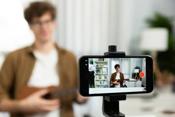 istock Influencer singing, playing guitar focus phone view on blur background. Gusher. 2031551804