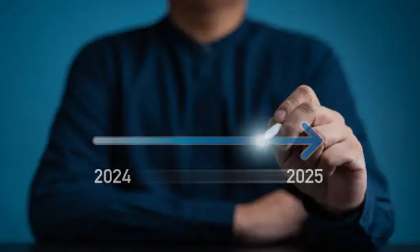 Photo of Businessman set a target for new year business goals 2025, positive indicators, company competitiveness on a global scale, rag virtual progress bar to change from 2024 to 2025 for next year beginning.