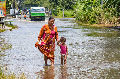 A mother and child walk through floodwaters in Gresik Regency, Indonesia, 21 February 2024.