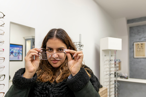 Young woman choosing glasses at the ophthalmologist. Healthcare, Eyesight And Vision Concept.