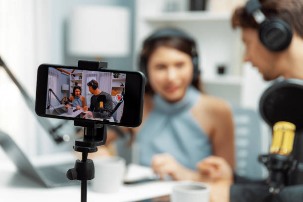 istock Focus on smartphone recording with blurry host channel broadcaster. Postulate. 2031663465