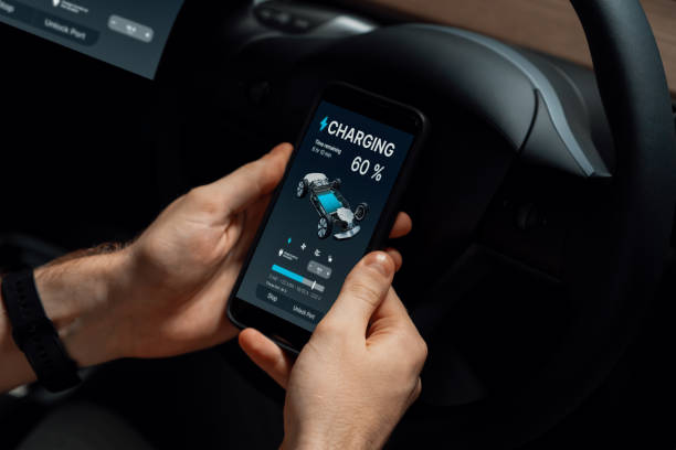 istock Electric car driver checks battery charging status app screen in car innards 2031680458