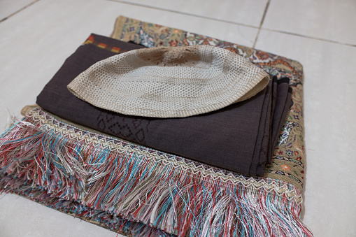 A sarong with a folded skullcap on top of a prayer mat. Prayer equipment, Ramadan month
