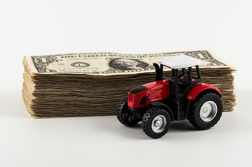 Miniature tractor and a stack of 1 US dollar bills