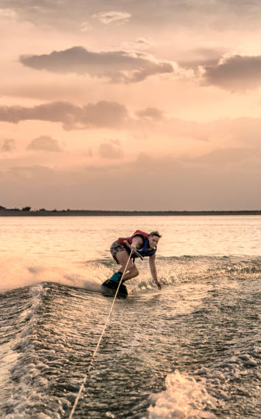 istock Young adult practicing wakeboarding, on lake at sunset. 2031807810