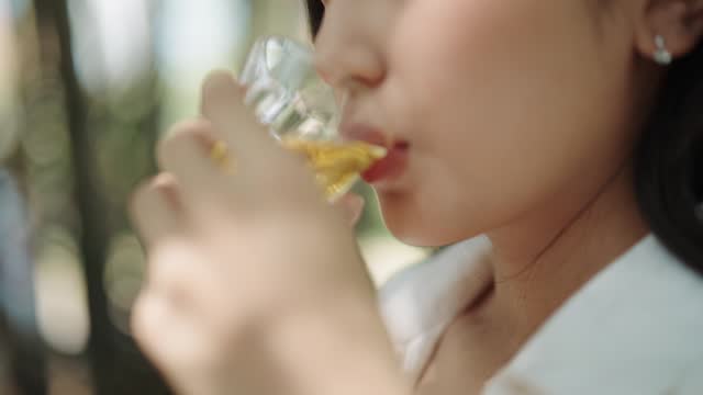 A closeup of a woman drinking hot herbal tea from the glass cup
