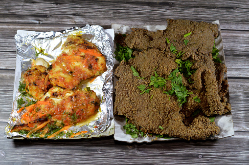 Arabic deep fried beef liver slices, beef liver covered with wheat bran, (Kebda Bel Rada) which means Fried bran liver and grilled fish fillet filet with carrot and parsley slices in a seafood sauce, selective focus