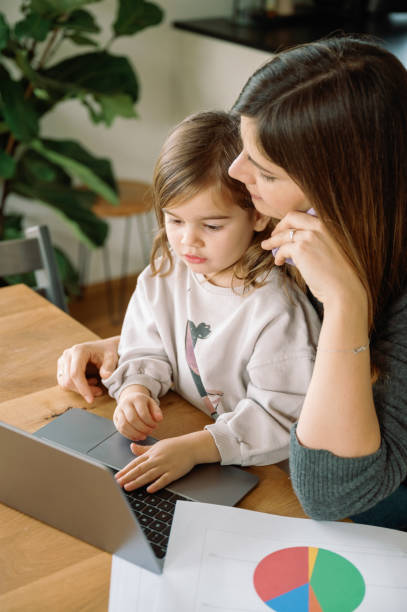 istock working mum talking on phone, business call, while daughter using laptop 2031853627