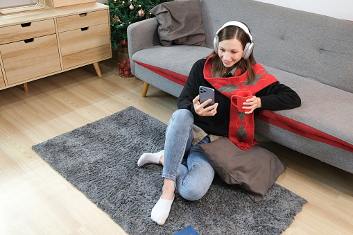 Care free young woman listening to music and enjoying the warm Christmas atmosphere at home..
