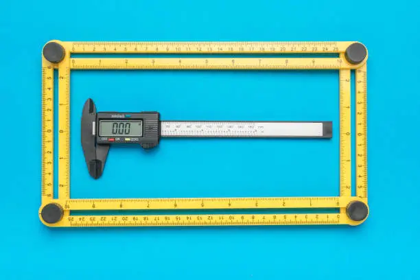 Universal measuring ruler and electronic vernier caliper on a blue background. A tool for accurate measurement of dimensions.