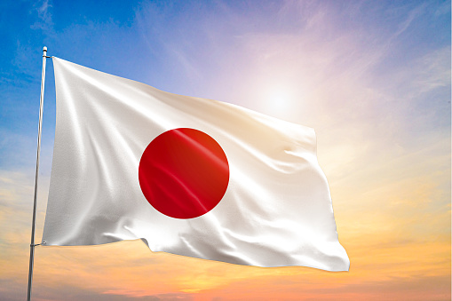 The National flag of Japan blowing in the wind in front of a clear blue sky