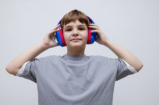 teenage boy with a smile holds blue purple headphones in his hands
