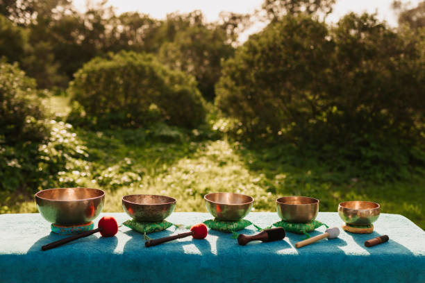 Five beautiful old Tibetan singing bowls on a massage table in a garden before to be used for a sound bowl therapy stock photo