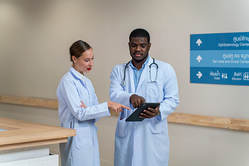 Black Male and Middle Eastern Female Doctors Reviewing Patient Checklists on Digital Tablet