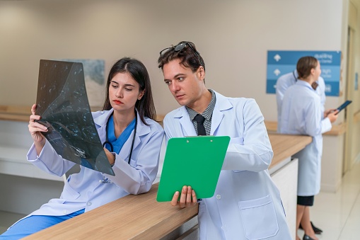 Diagnostic Collaboration: White Male and Multiracial Female Doctors Analyzing Patient X-Ray Film